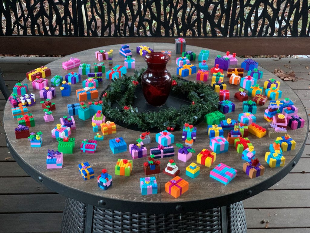 Over 100 colourful LEGO-built gifts on a round table with a green wreath and red vase in the centre.